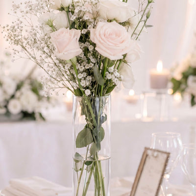 Elegant white rose wedding centerpiece in a glass vase with candles