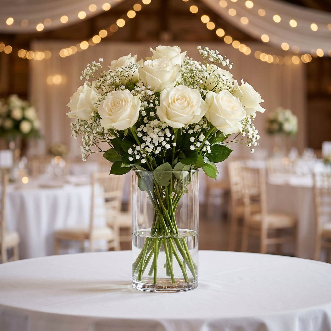 White rose wedding centerpiece in glass vase on decorated reception table