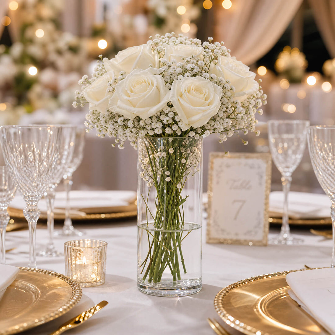 Elegant white rose wedding centerpiece with gold table settings and candles