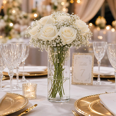 Elegant white rose wedding centerpiece with gold table settings and candles