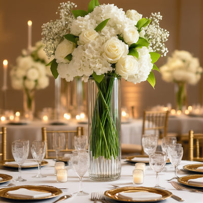 Elegant white floral arrangement in a tall glass vase on a decorated dining table.