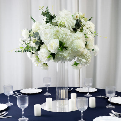 Elegant white floral centerpiece on a table with candles and glassware.