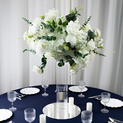Elegant white floral centerpiece in a clear vase on a dark table setting.