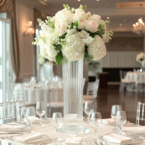 Elegant floral centerpiece in a tall glass vase for a wedding reception.
