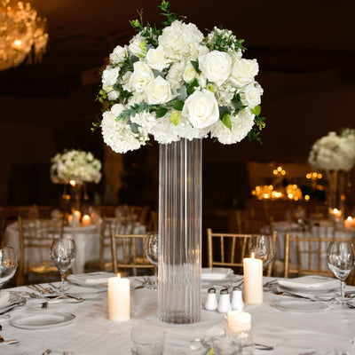 Elegant white floral centerpiece in crystal vase on a beautifully set dining table.