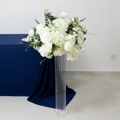 White floral arrangement in a clear vase on a blue table.