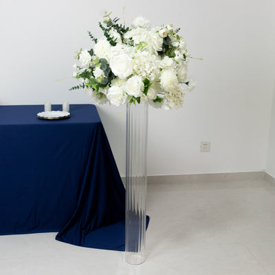 White floral arrangement in a clear vase on a table with a navy tablecloth.