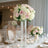 Elegant floral arrangement in a tall glass vase at a beautifully set dining table.
