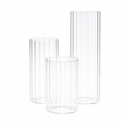 Three clear ribbed glass cylinders on a white background