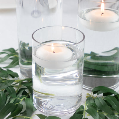 Floating candle in a glass with water and greenery accents.