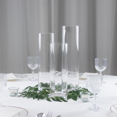Elegant glass vases on a table with greenery and dinnerware