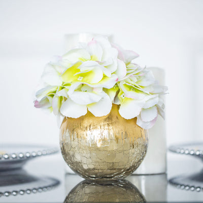 Gold vase with white and green flowers, elegantly styled.
