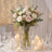 Elegant wedding table centerpiece with pastel roses, candles, and glass vase