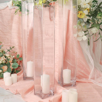 Clear glass vases with candles on a pink draped surface
