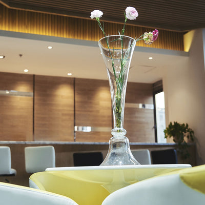Elegant glass vase with flowers on a table in a modern interior setting.
