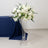 Elegant white floral arrangement in a tall glass vase.