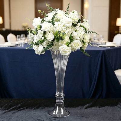 Elegant white floral centerpiece in a tall glass vase on a banquet table
