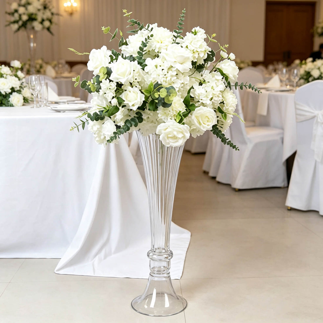 White wedding floral centerpiece in tall glass vase on banquet table