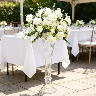 White floral wedding centerpiece in tall glass vase on outdoor reception table