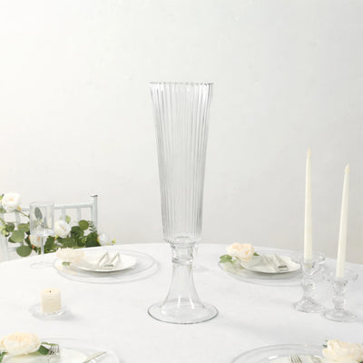 Elegant tall glass vase with ribbed design on a dining table.