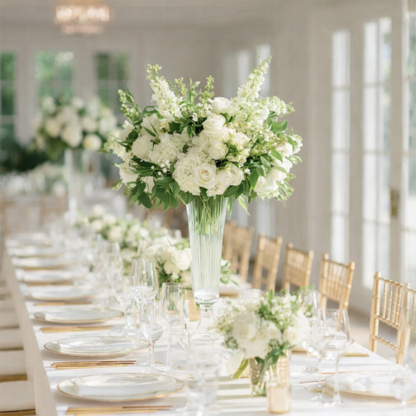 Elegant white floral arrangement in a glass vase on a beautifully set dining table.