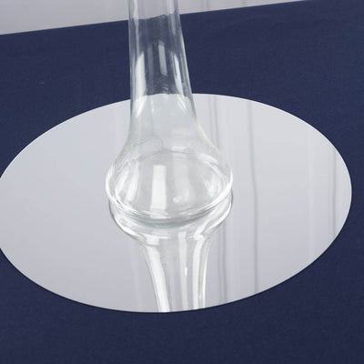 Glass carafe reflecting on a round mirror base.