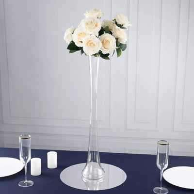 Elegant tall vase with white roses on a dining table setting.