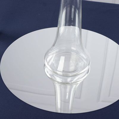 Clear glass vase on a reflective circular surface.