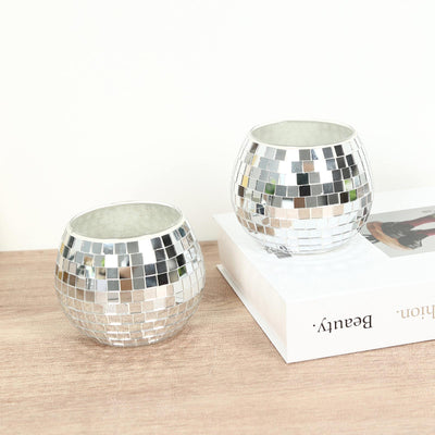 Mirrored mosaic candle holders on a wooden surface with white background