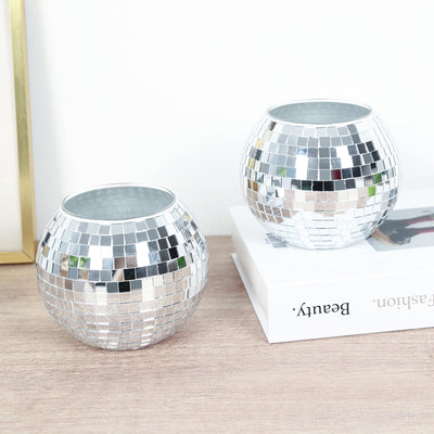 Silver mosaic candle holders on a wooden table with a white book backdrop