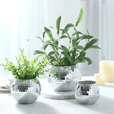 Silver mosaic vases with green plants on a bright table centerpiece