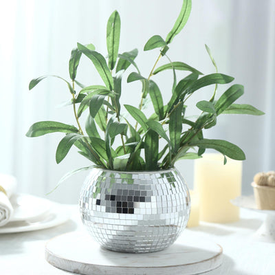 Mirrored mosaic vase with green leafy plant on a white table