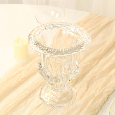 Elegant glass vase with intricate design on a soft fabric backdrop.