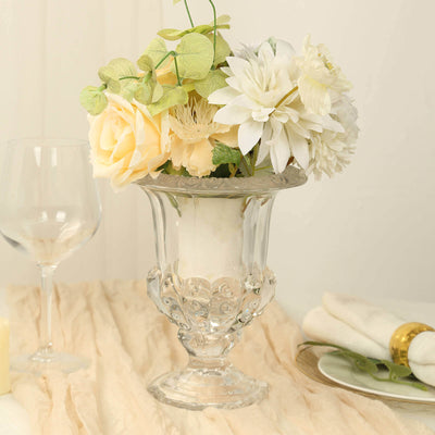 Elegant glass vase with white and pastel flowers, set on a soft tablecloth.