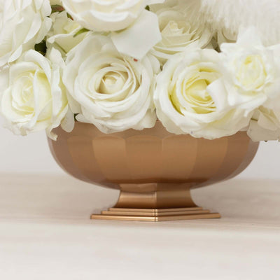 Gold pedestal vase with white roses arrangement.
