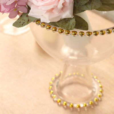 Glass vase with gold bead trim and floral arrangement.