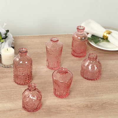 Set of decorative pink glass bottles on a wooden surface.