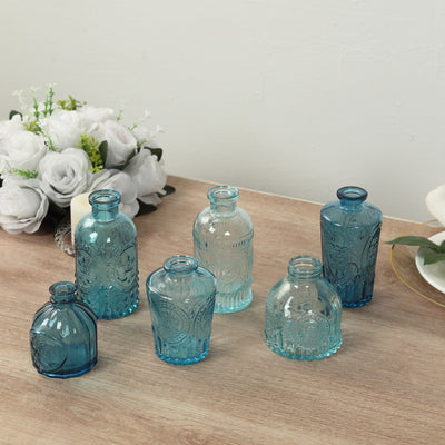 Set of six decorative glass vases in varying blue tones on a wooden surface.