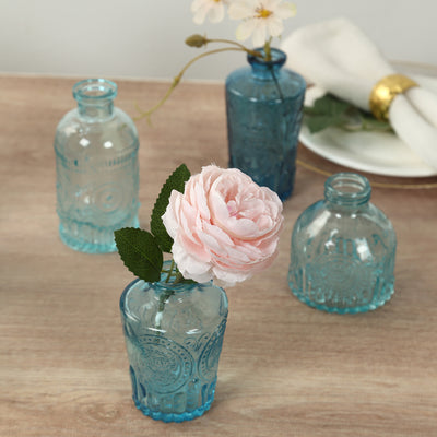 Blue decorative glass vases with flowers on a wooden surface.