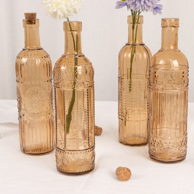 Decorative amber glass bottles with floral accents on a neutral background.