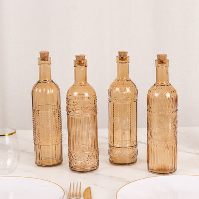 Set of four decorative amber glass bottles with cork stoppers.
