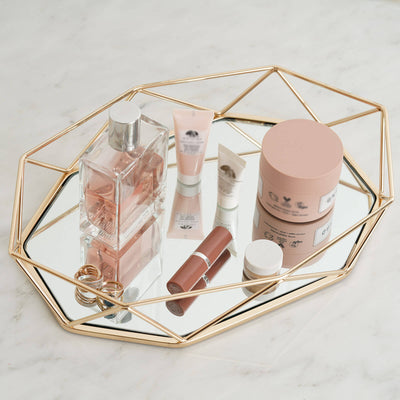 Beauty products on a stylish mirror tray with a gold geometric design.