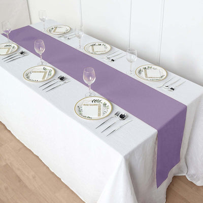 Purple table runner on a dining table set with plates and glasses.