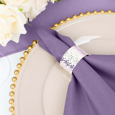 Elegant purple napkin with silver napkin ring on a decorative plate.
