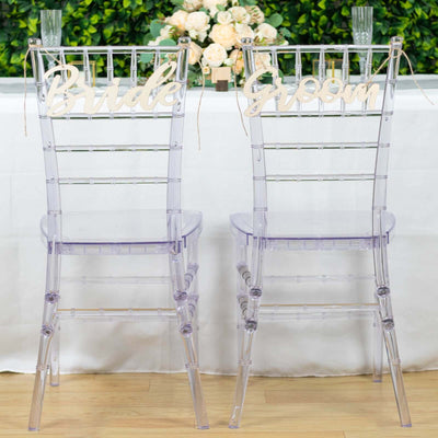 Clear acrylic wedding chairs labeled "Bride" and "Groom" for elegant decor.