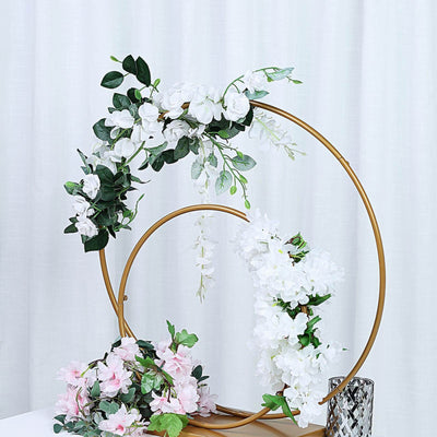 Floral arrangement on a gold circular stand with pink and white flowers.