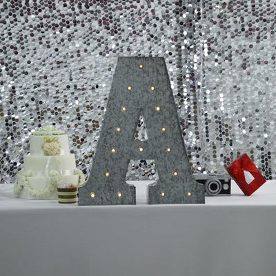 Decorative marquee letter "A" with lights, set against a sparkling backdrop.