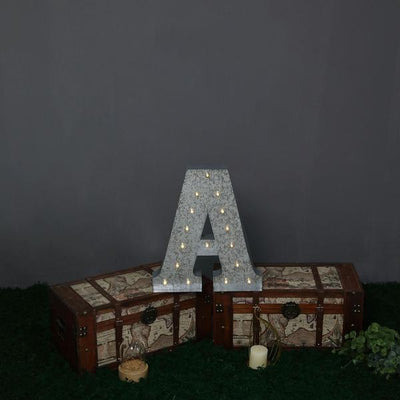 Decorative letter "A" with lights, placed on vintage trunks.