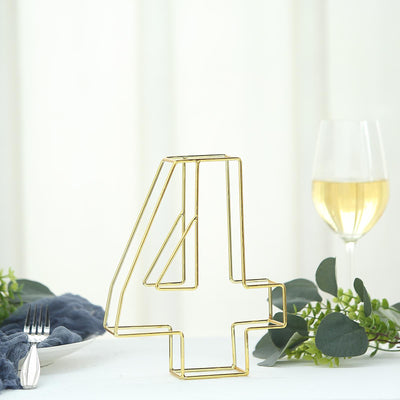 Gold wire number 4 table decor with wine glass and foliage in soft setting.