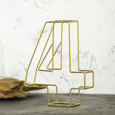 Gold wire number 4 sculpture on a textured surface.